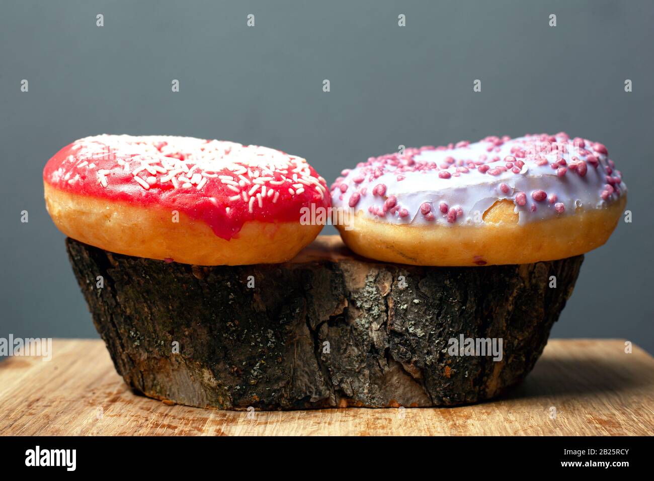 dolci dolci con glassa. ciambelle colorate su moncone di legno. Foto Stock