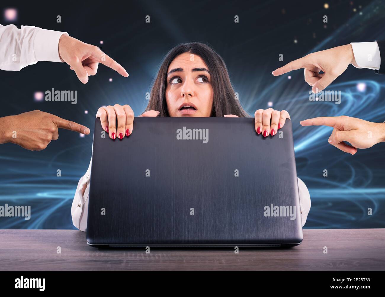 La ragazza impaurita si nasconde dietro il portatile. È vittima del cyberbullismo Foto Stock