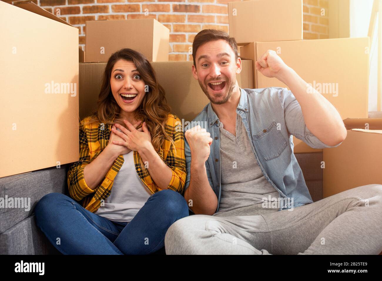 La coppia felice ha trovato una nuova casa e hanno bisogno di organizzare tutti i pacchetti. Concetto di successo, cambiamento, positività e futuro Foto Stock