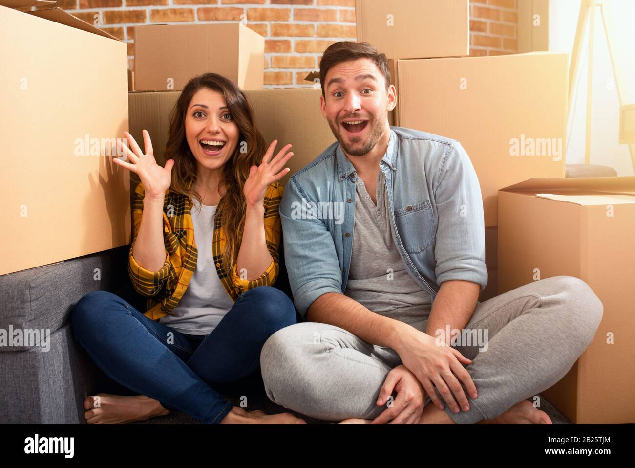 La coppia felice ha trovato una nuova casa e hanno bisogno di organizzare tutti i pacchetti. Concetto di successo, cambiamento, positività e futuro Foto Stock