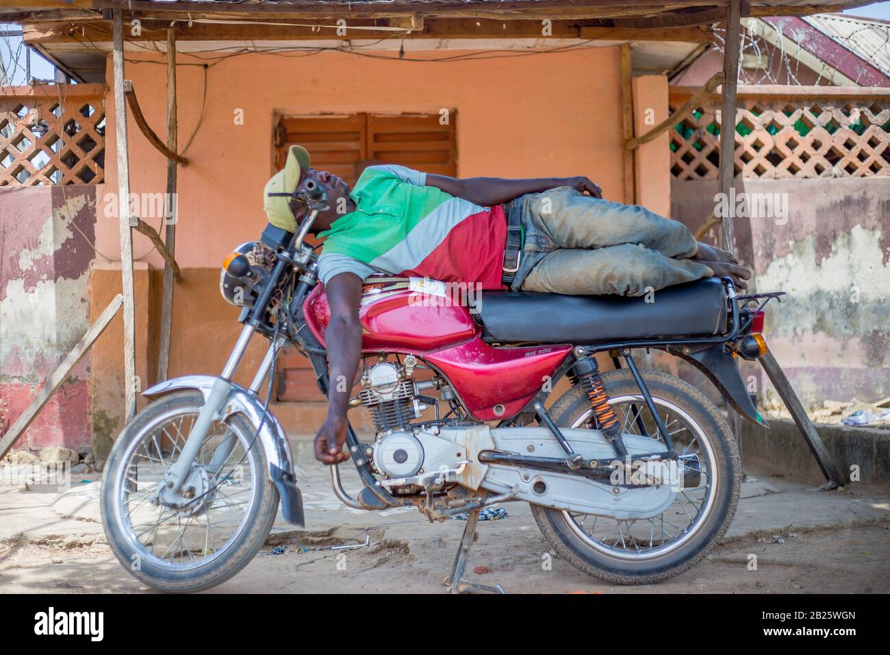 I tassisti del motociclo (okada) prendono un pisolino sulle loro bici in Nigeria. Foto Stock