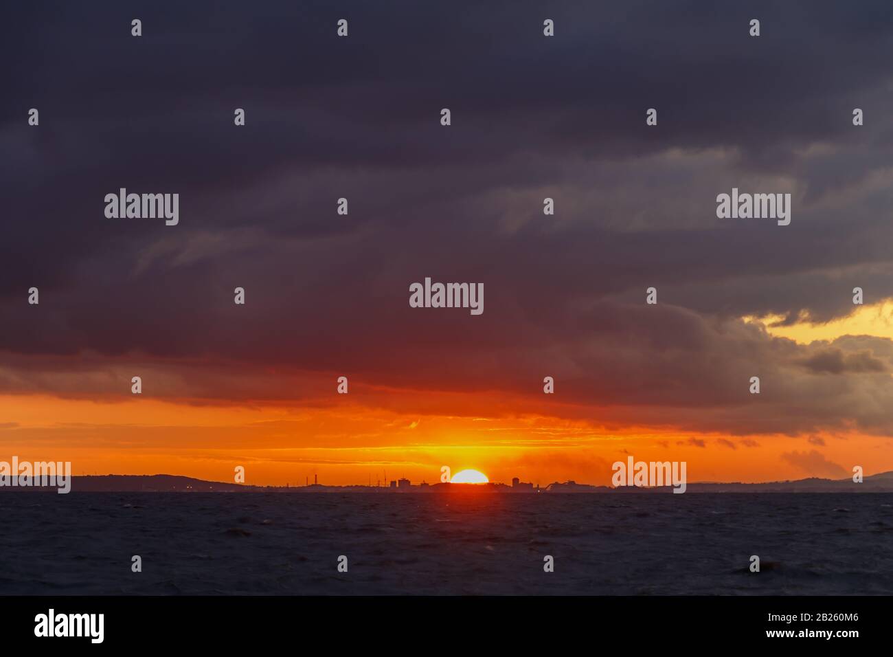 Dalla spiaggia di Clevedon guardando attraverso il canale di Bristol, mentre il sole tramonta su Cardiff Foto Stock