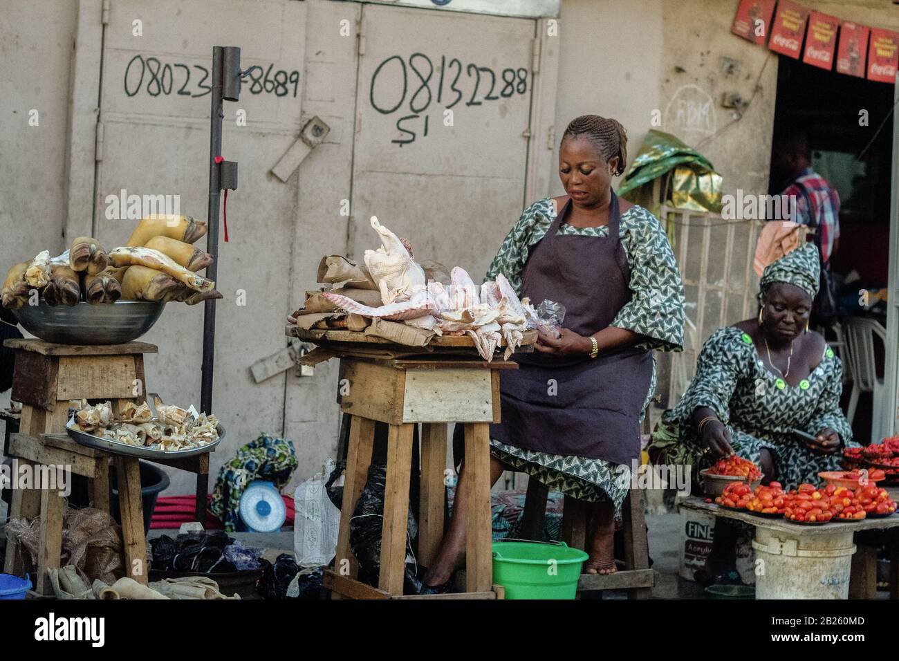 Due donne mostrano i loro beni in un mercato stradale su una strada a Lagos, Nigeria. Foto Stock