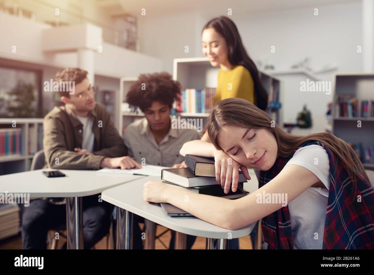 La ragazza stanca dorme sopra i libri durante un incontro con gli studenti. Concetto di stress e straordinari Foto Stock