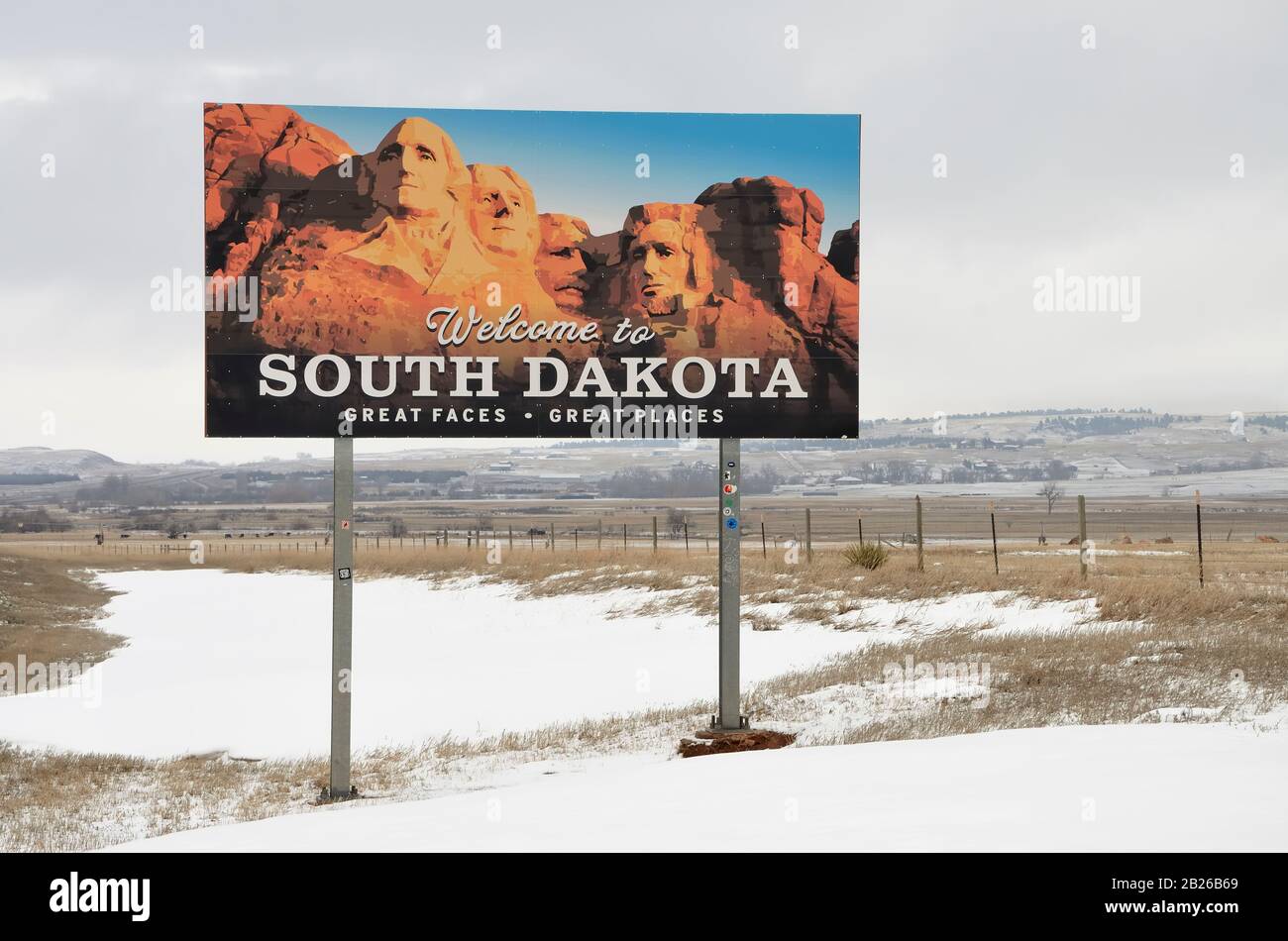 Cartello stradale che indica l'ingresso nello stato del South Dakota, Stati Uniti d'America. Sullo sfondo grigio cielo e prato innevato. Foto Stock