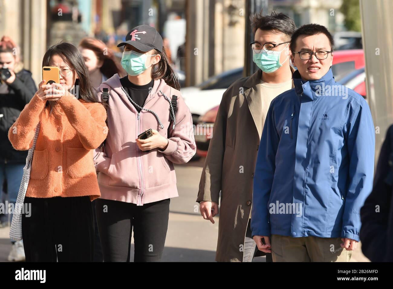 Persone che indossano maschere facciali prima della parata del giorno di San David a Cardiff. Foto Stock
