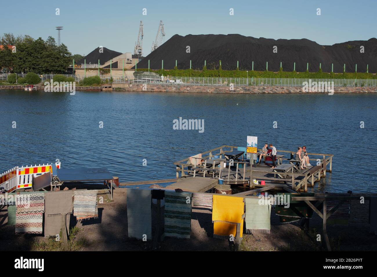 I cittadini di Helsinki partecipano alla tradizione per pulire i tappeti della riva del mare in un luogo speciale nella centrale di Hanasaari a Helsinki, Finlandia Foto Stock