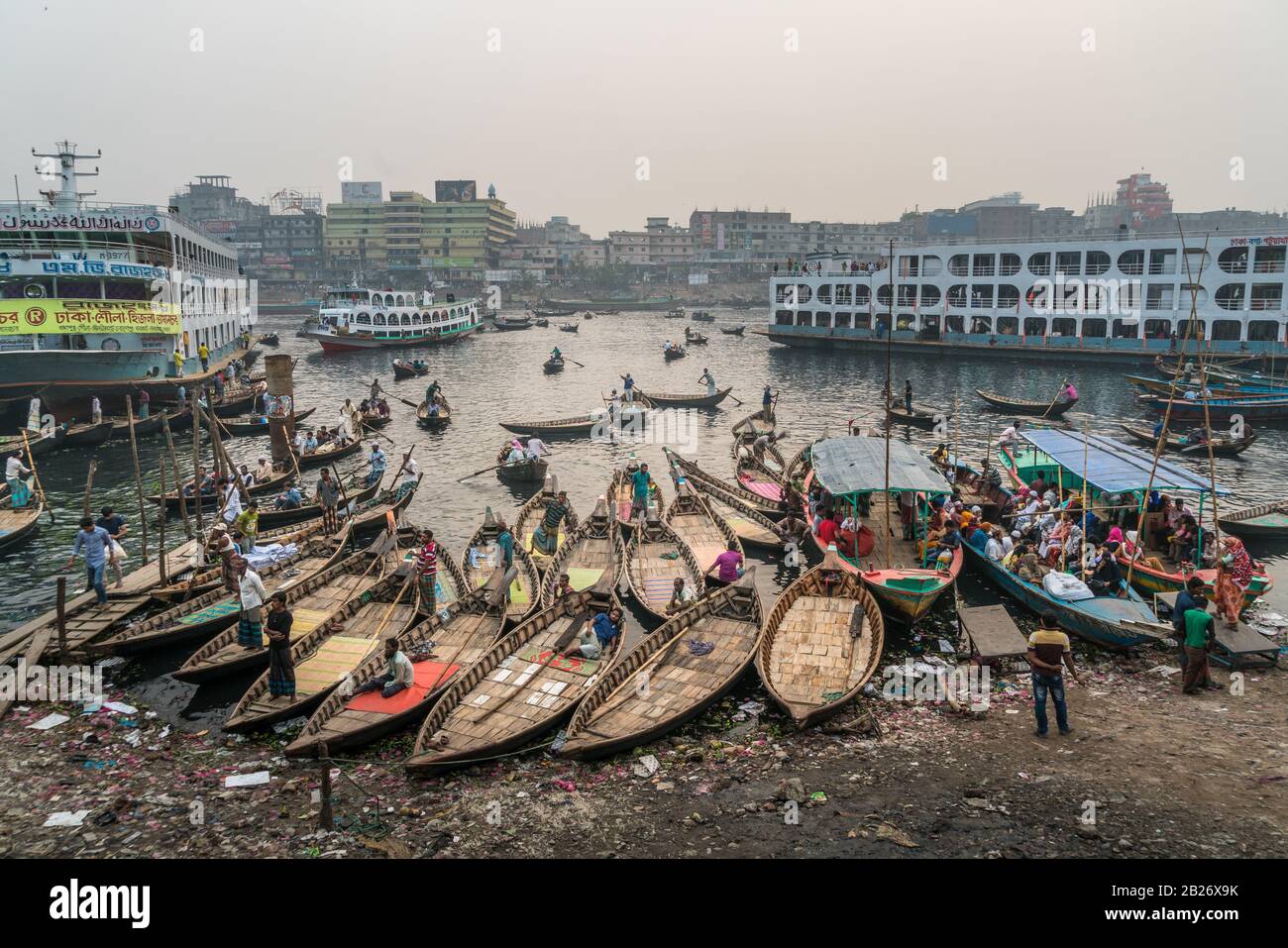 Barche, traghetti, lettiere e persone in un trafficato molo fluviale e porto di Dhaka, in Bangladesh Foto Stock