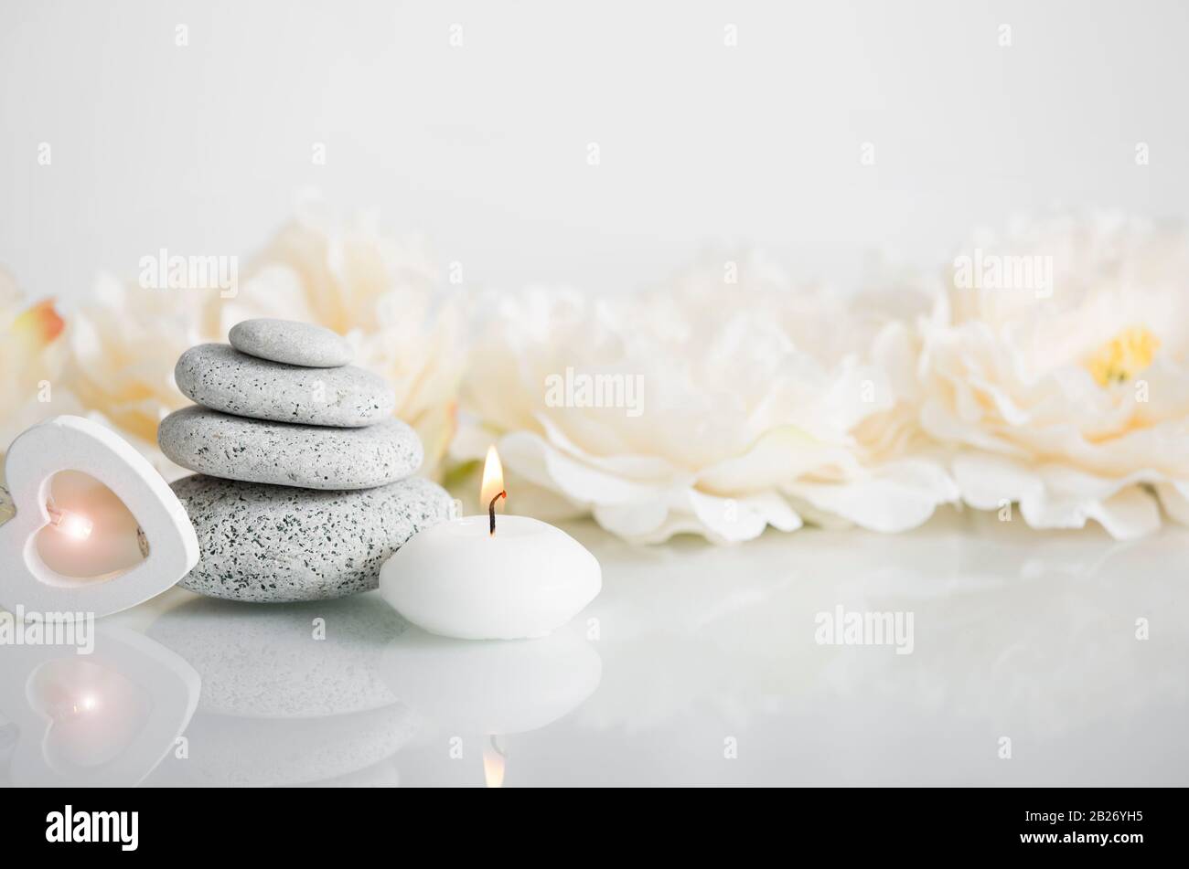 Equilibrio minimalista zen pietra bellezza prodotti sfondo con luce di cuore in legno, spa candela a fuoco e bella riflessione. Sfondo pubblicitario. Foto Stock