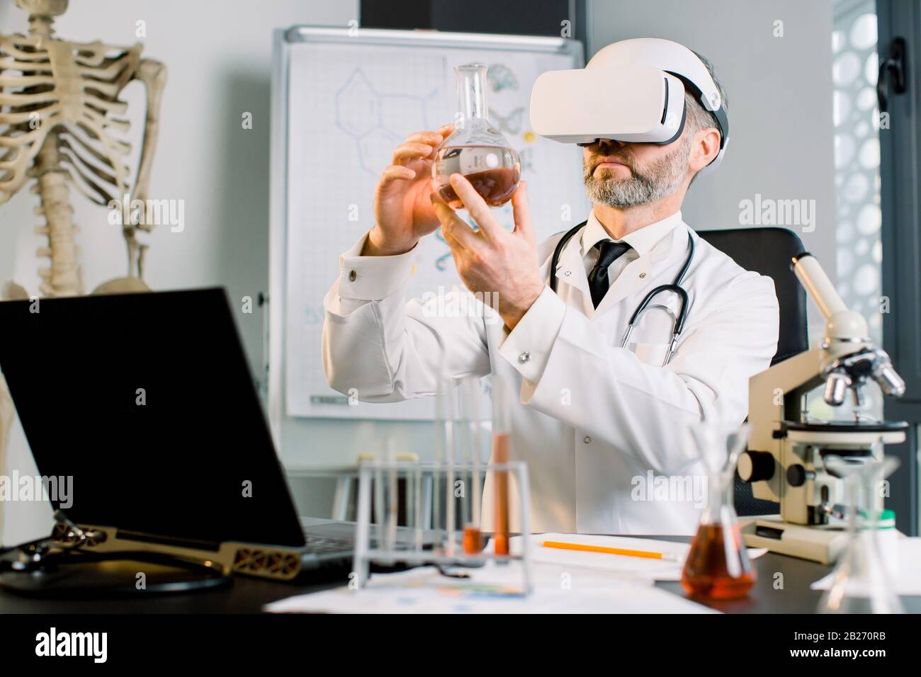 Medico caucasico, scienziato, virologo, indossando occhiali per la realtà virtuale per l'immaginazione, conducendo ricerche in laboratorio, tenendo fiasca Foto Stock