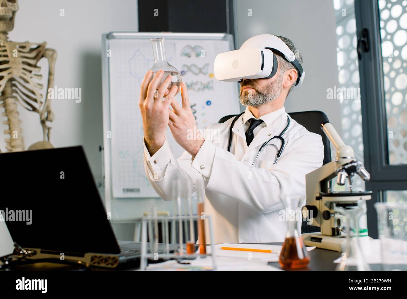 Medico caucasico, scienziato, virologo, indossando occhiali per la realtà virtuale per l'immaginazione, conducendo ricerche in laboratorio, tenendo fiasca Foto Stock