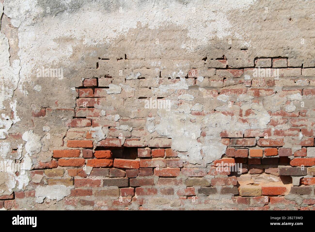 una bella vecchia decading cemento e mattoni rossi parete esterna esposta e cadere a parte Foto Stock