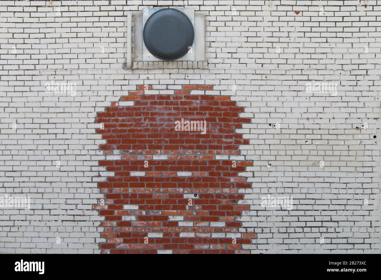 una vernice bianca retro che si stacca e un muro di mattoni rossi sbiaditi Foto Stock