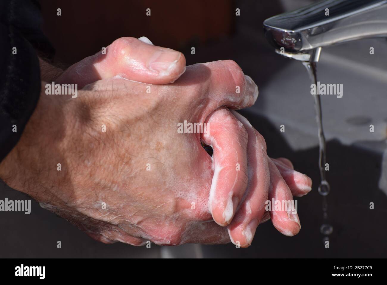 Un uomo lavando accuratamente le mani con acqua e sapone per prevenire la diffusione di Coronavirus / Covid-19 Foto Stock