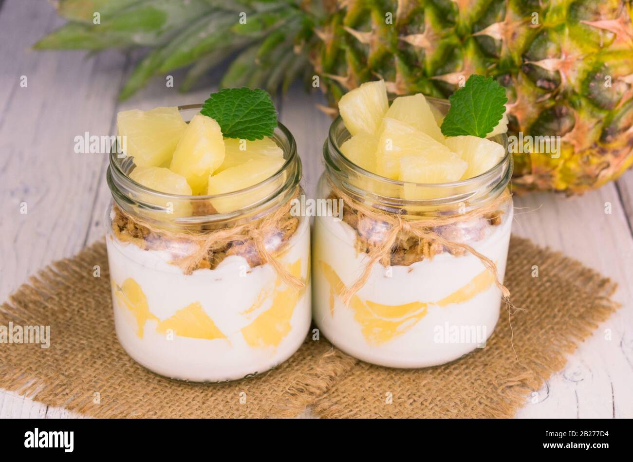 Due vasetti di yogurt all'ananas fatto in casa. Un concetto di dessert leggeri e sani. Foto Stock