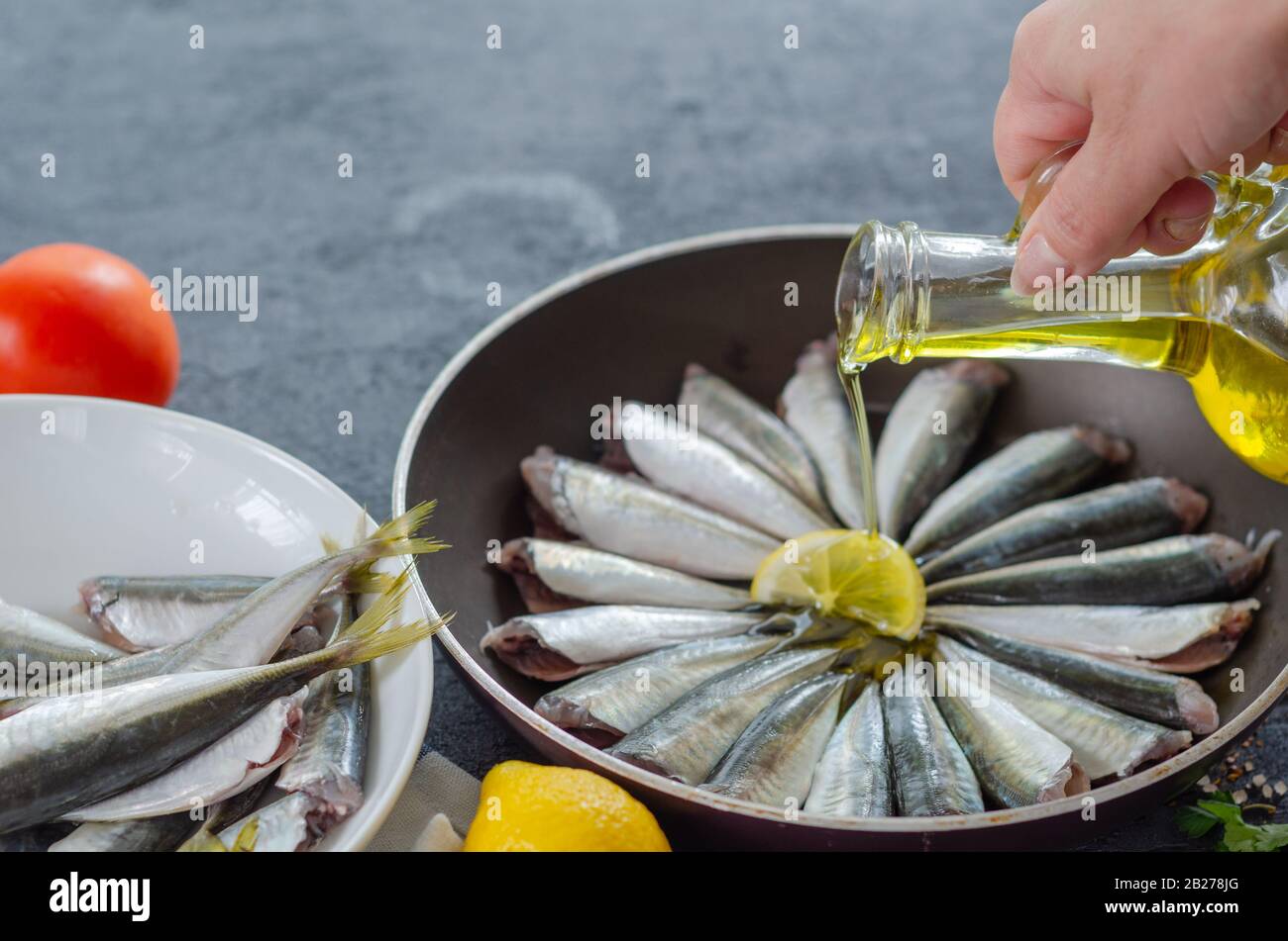 Donna sta versando olio di oliva nella padella. Foto Stock