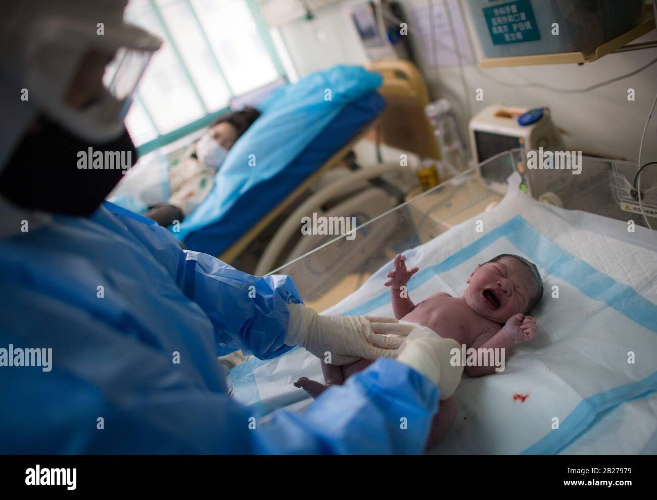L'ostetrica Wu Dan si prende cura del bambino di Liu Ting nella sala di consegna del Wuhan Maternal and Child Health Hospital di Wuhan, nella provincia Hubei della Cina centrale, il 1° marzo 2020. All'inizio della mattinata del 29 febbraio, il volontario Wang Zhen scacciò dalla sua comunità subito dopo aver ricevuto una richiesta di aiuto da una donna incinta che viveva a 30 chilometri di distanza in un'altra comunità a Wuhan. Wang portò la donna incinta e la sua famiglia al Wuhan Maternal and Child Health Hospital, dove la donna partorì in modo sicuro il suo bambino. Il 23 gennaio, Wang Zhen, un fotoricettore del calcolatore Foto Stock