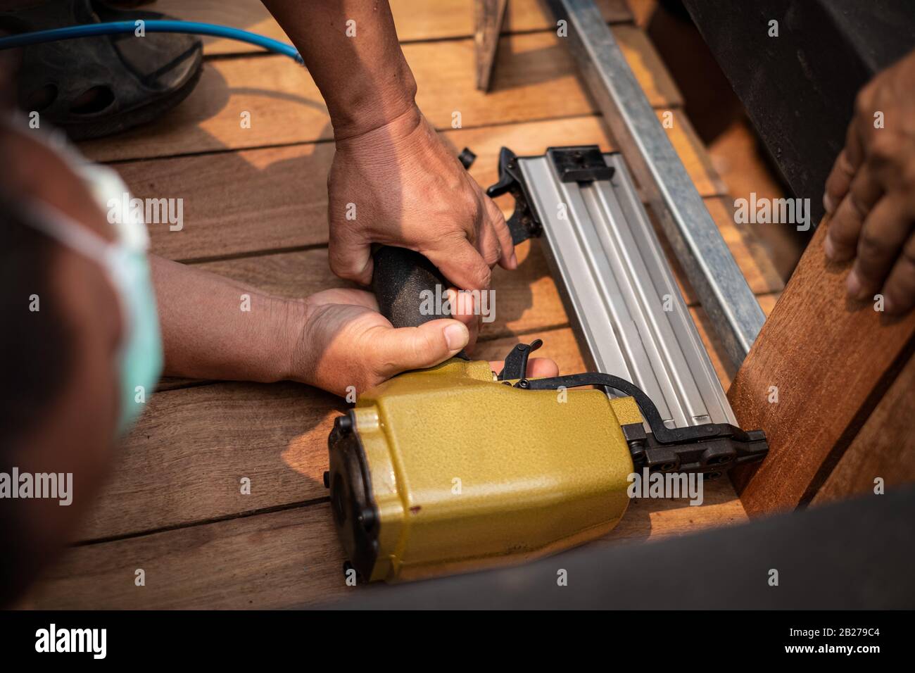 Primo piano di un carpentiere manuale con pistola ad aria per completare il tavolo in legno in giardino Foto Stock