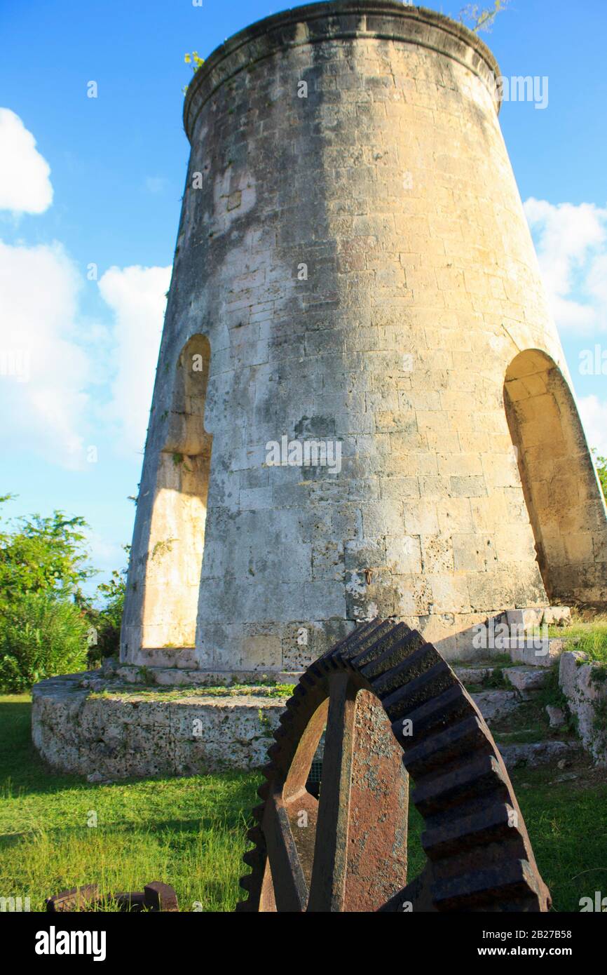 Vecchio mulino a vento e ruota dentata sul verde terreni erbosi di Chateau Murat a Marie Galante Guadalupa durante un tramonto con cielo blu e nuvole bianche Foto Stock