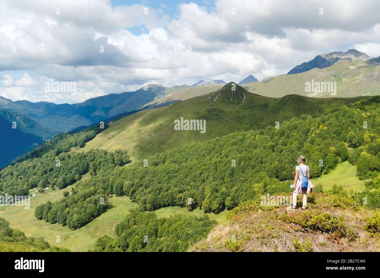 Donna con uno zaino blu sopra una gola della valle di montagna Foto Stock