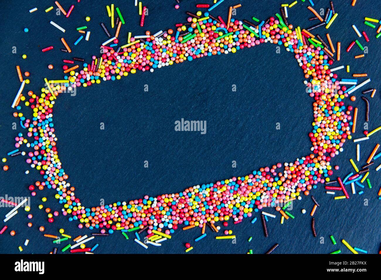 Biglietto d'auguri di Pasqua con cornice colorata e uova di Pasqua, coniglietto al cioccolato e uova. Vista dall'alto sul tavolo in pietra con spazio per i tuoi saluti Foto Stock