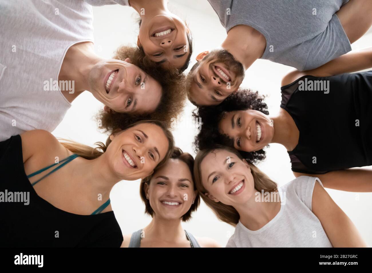 Persone multietniche in piedi in cerchio si sono appoggiate per guardare la macchina fotografica Foto Stock