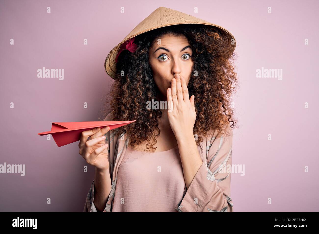 Giovane bella donna con capelli ricci e piercing indossare cappello  asiatico tenendo carta piano di copertura bocca con la mano scioccata con  vergogna per errore, esprimere Foto stock - Alamy