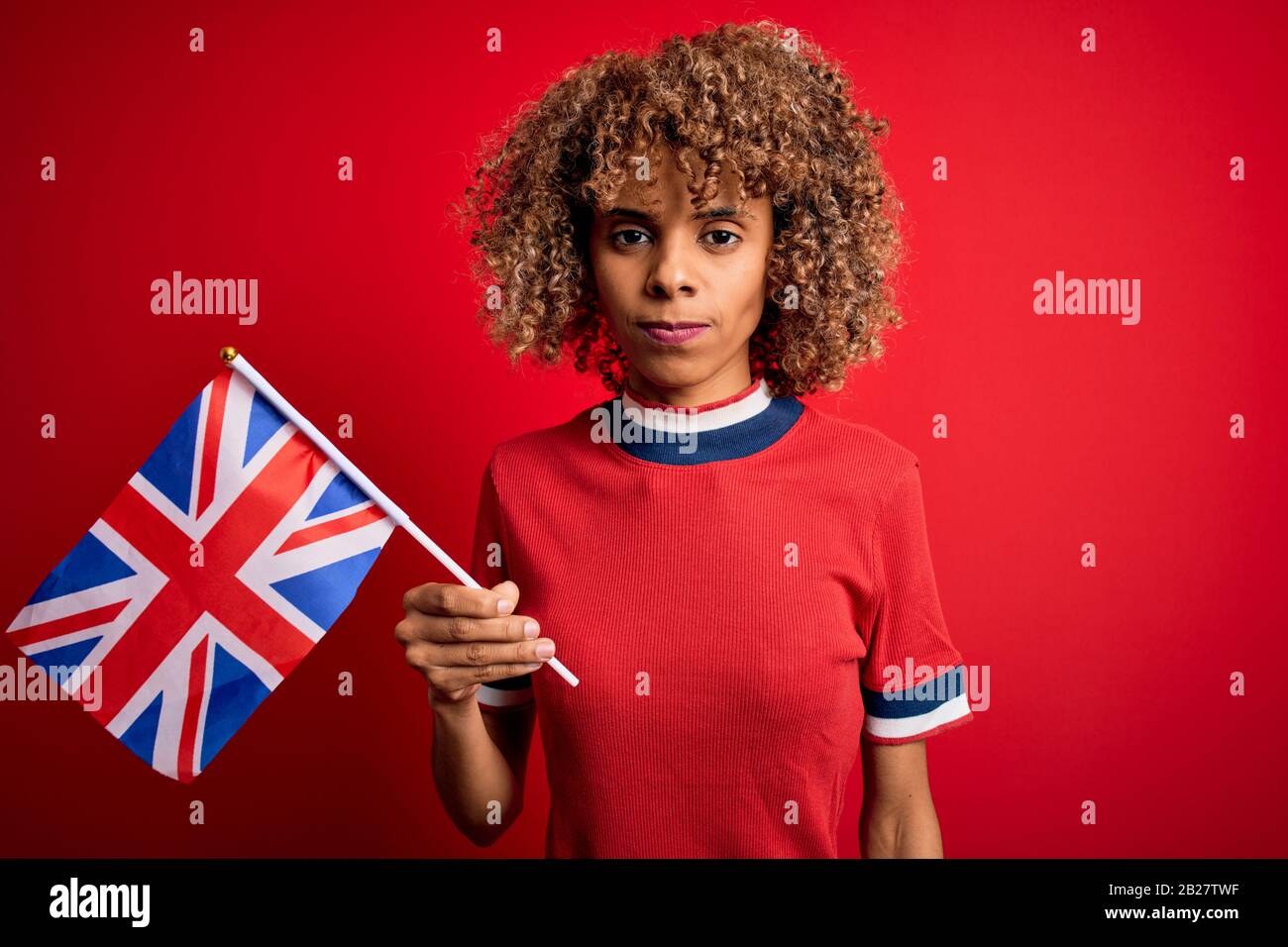 La giovane donna maledetta afroamericana che tiene la bandiera britannica per celebrare il referendum sulla brexit con un’espressione fiduciosa sul volto intelligente che pensa seriamente Foto Stock