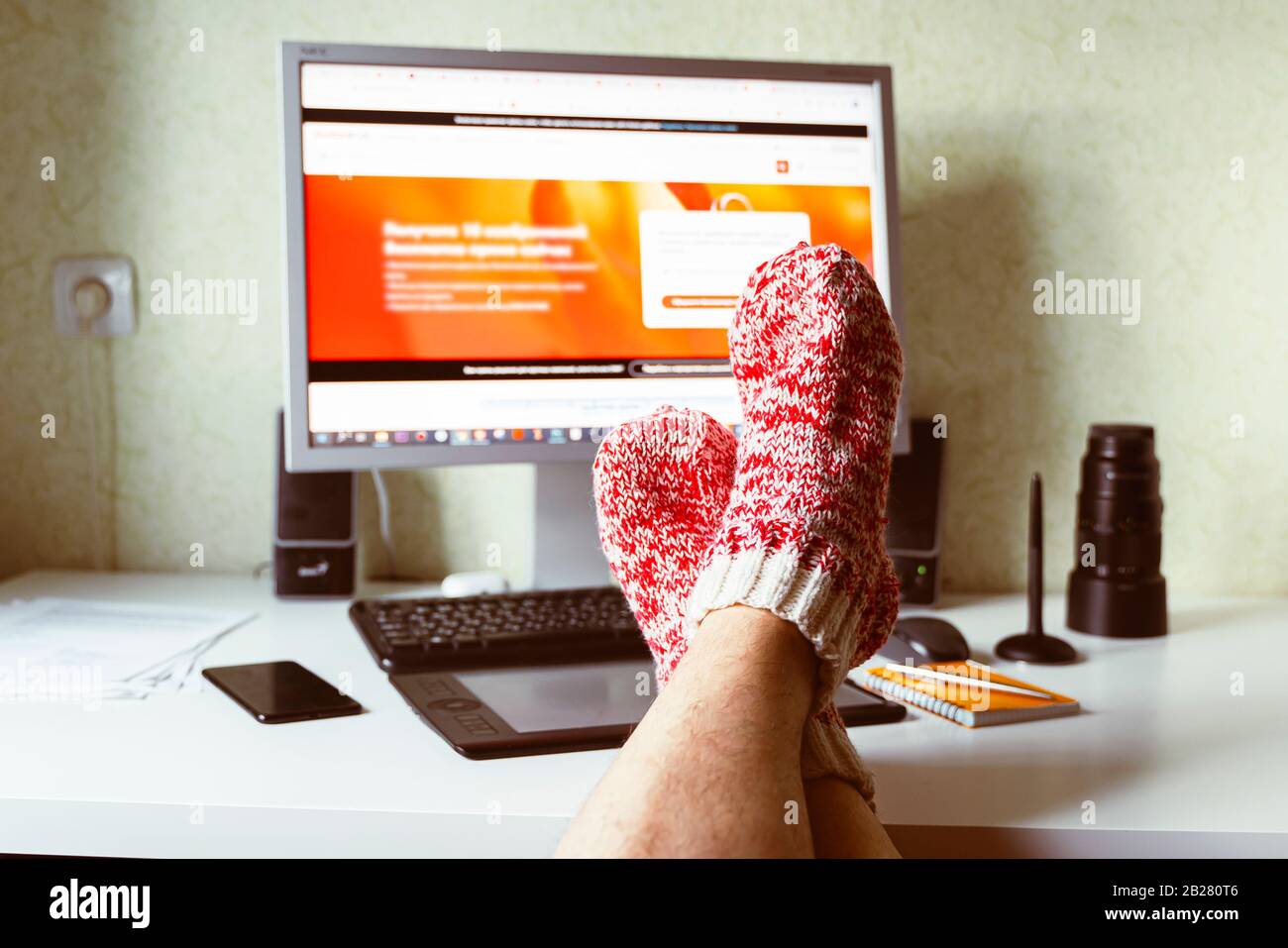 Lavoro autonomo a casa su un monitor per computer. Studiare e lavorare online, freelance, calzini caldi, inverno, casa comfort e relax Foto Stock