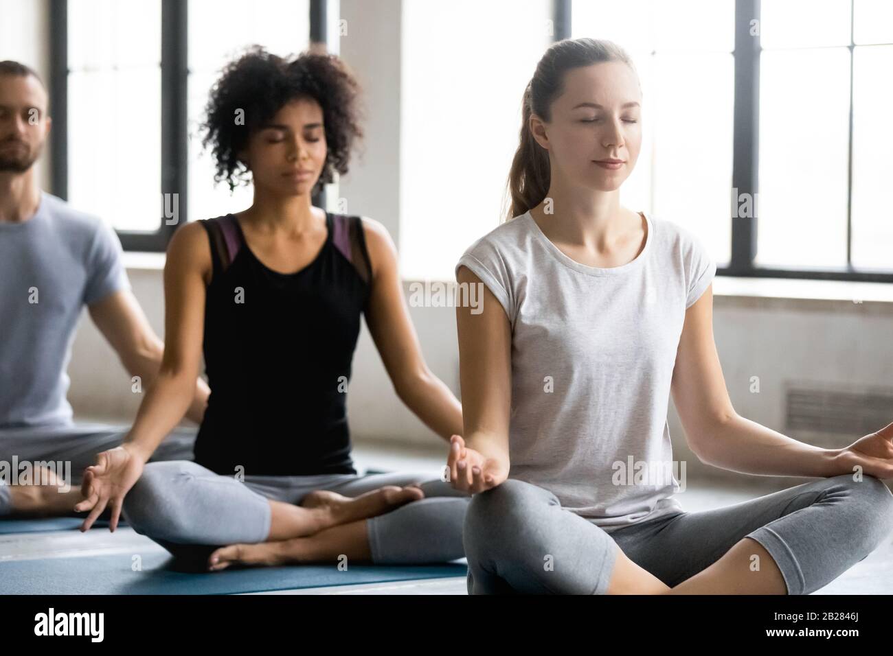 Donna caucasica seduto in posizione di loto fare pratica di meditazione al chiuso Foto Stock