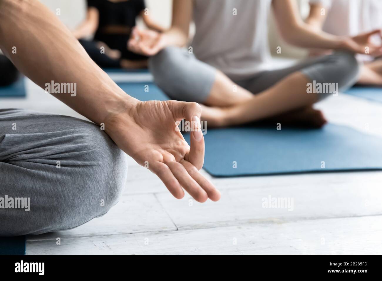 Yogi sedersi in posa di loto fuoco di closeup sulle dita piegate Foto Stock