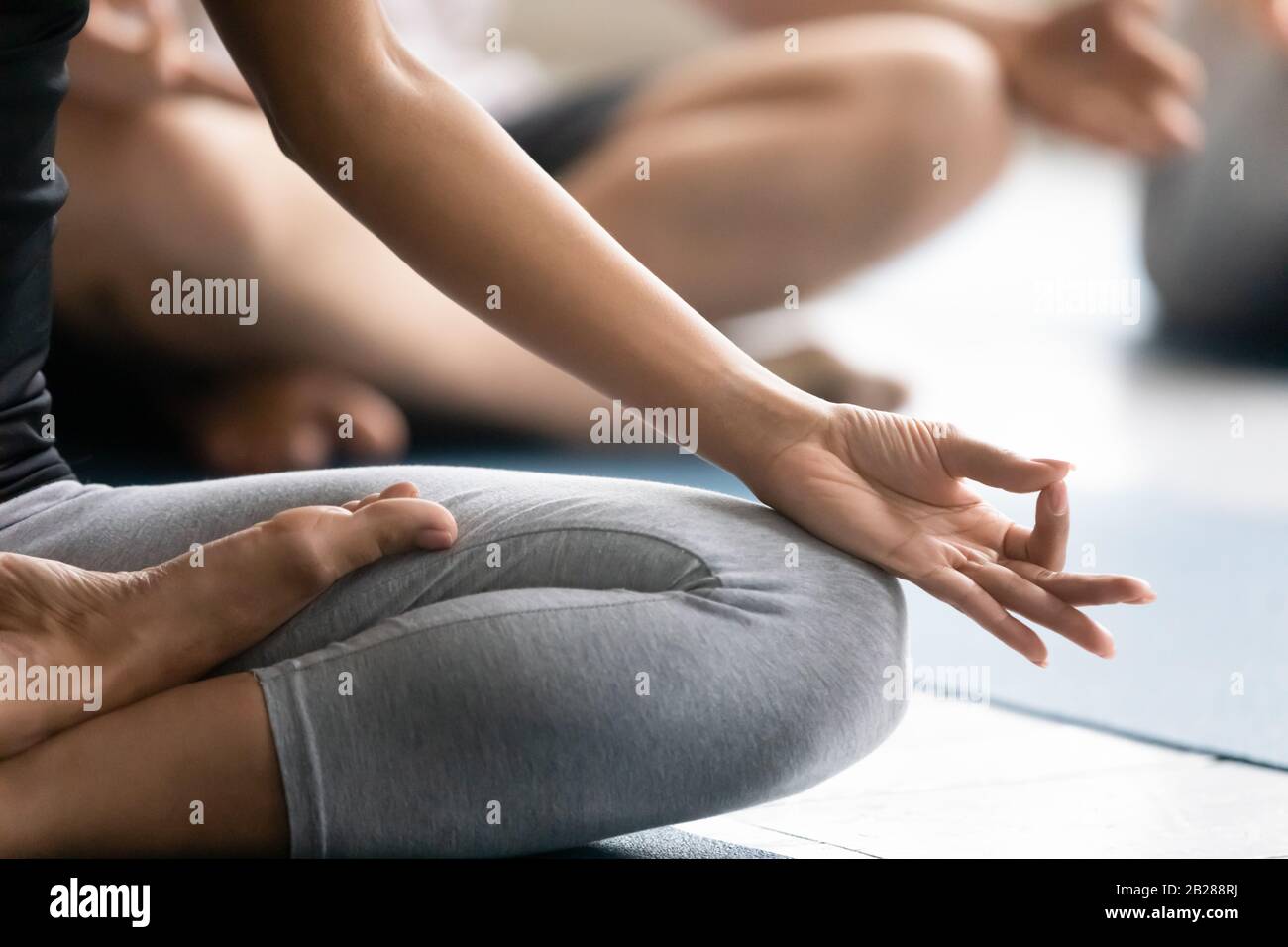 Donna seduta in posizione lotus primo piano fuoco sul simbolo Gyan Foto Stock