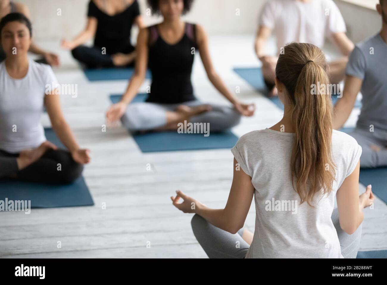 Coach e gruppo di persone che meditano seduti in posa di loto Foto Stock