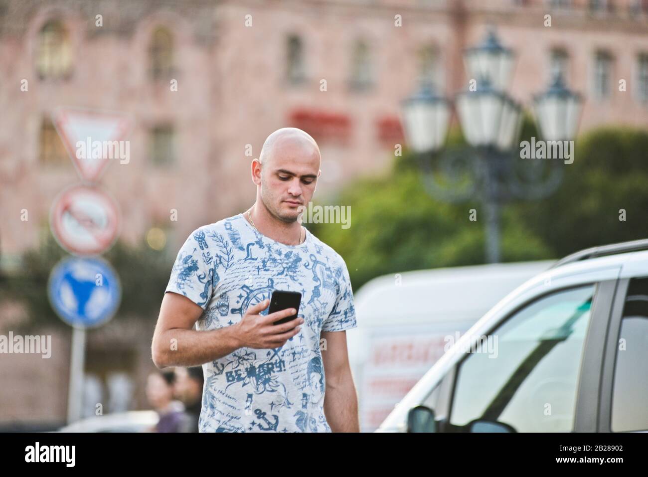 Un giovane armeno che guarda il suo cellulare in Piazza della Repubblica, Yerevan. Armenia Foto Stock
