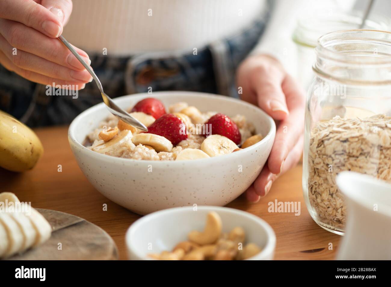 Donna che mangia porridge di farina d'avena con frutta. Concetto di stile di vita sano e dieta. Calda mattina leggera, sana colazione su tavolo di legno Foto Stock