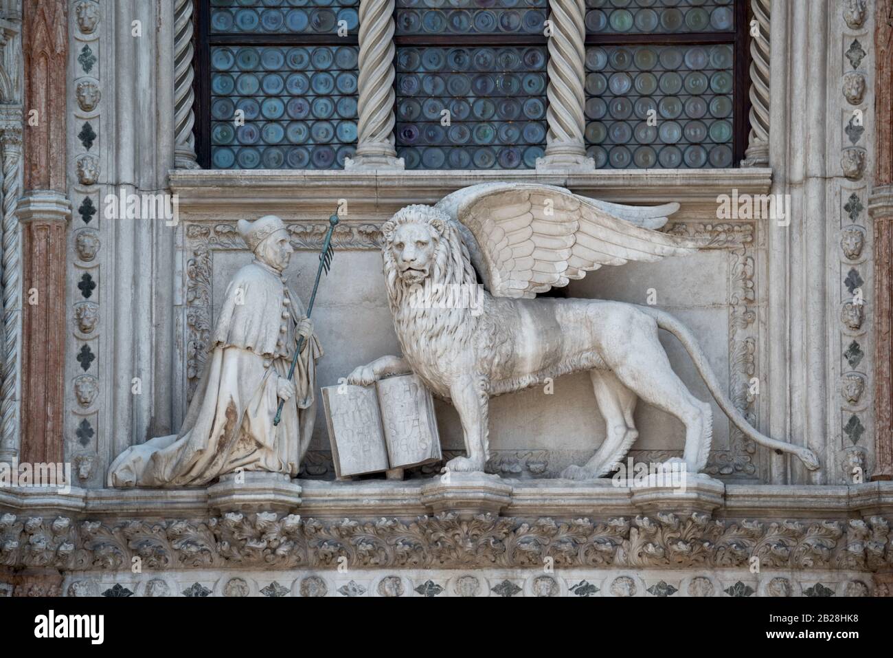 Leone alato e un sacerdote con una Bibbia in Piazza San Marco, Palazzo dei Dogi. Frammento di ingresso di Palazzo Ducale. Il Leone è il simbolo di Venezia. Foto Stock