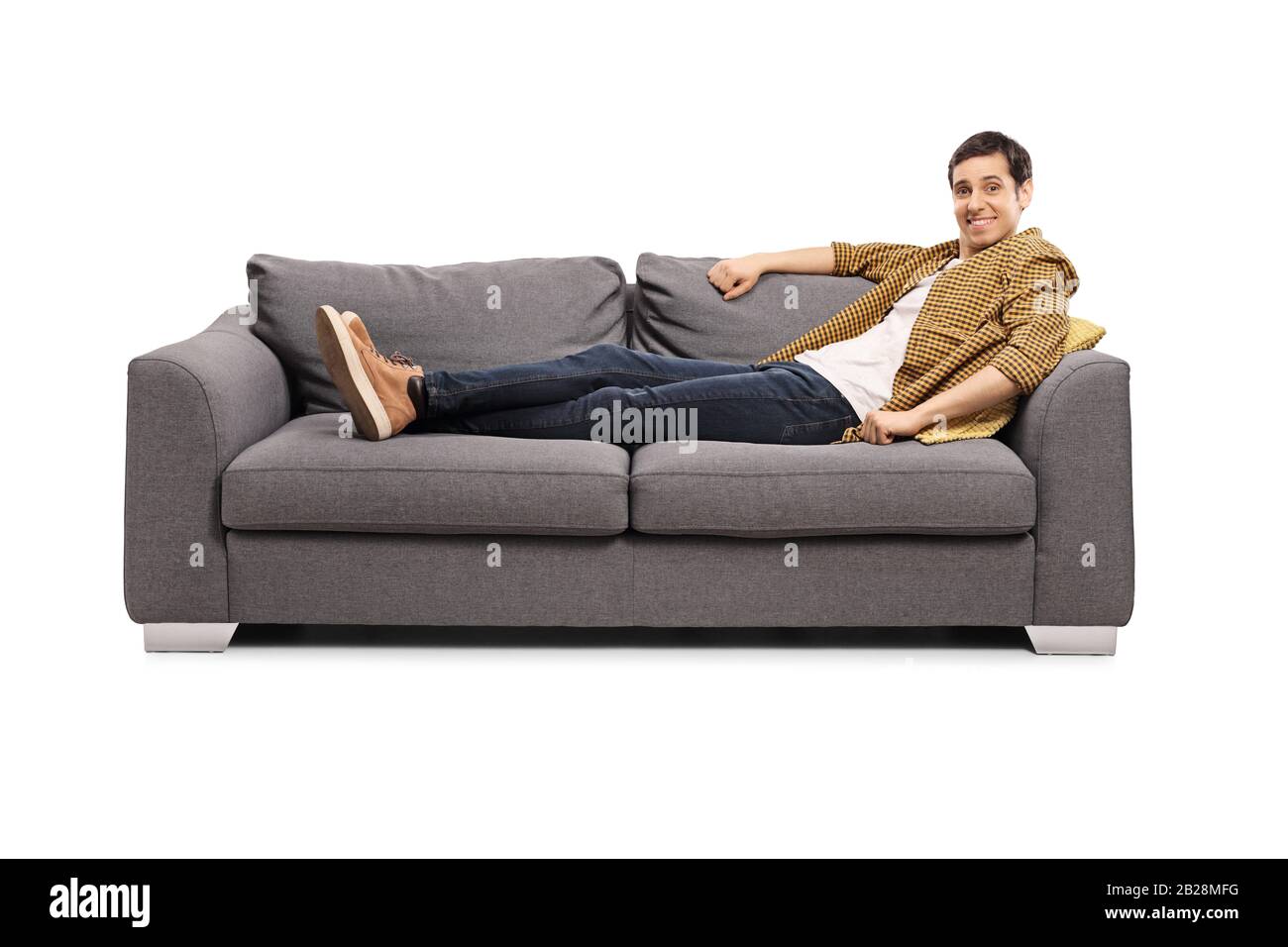 Giovane uomo casual sdraiato su un divano e sorridente alla macchina fotografica isolato su sfondo bianco Foto Stock