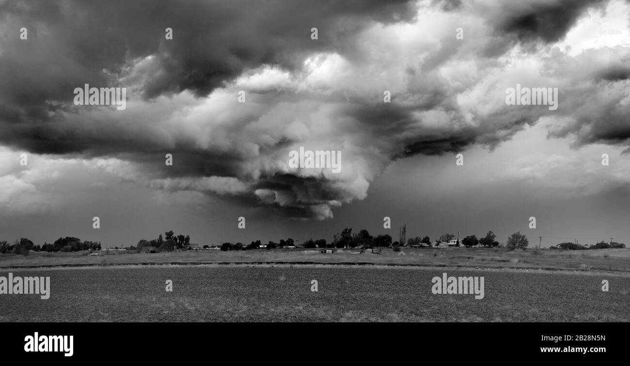 Monocromia di minacciosa e minacciosa nuvola a imbuto in un giorno tempestoso sopra l'area popolata Foto Stock