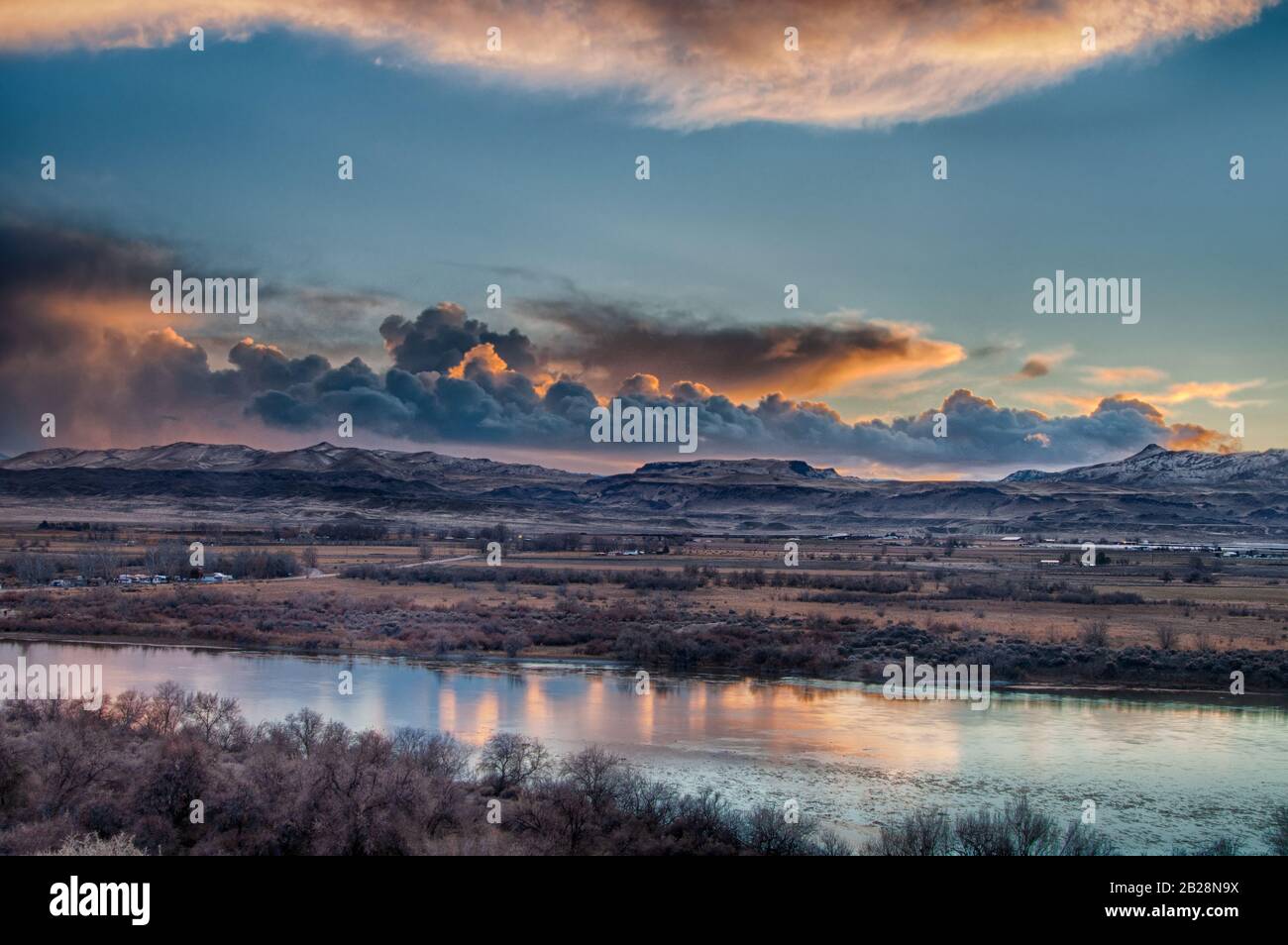 Tramonto scuro e fading sole illuminato nuvola coperta cielo in tarda serata guardando sopra il fiume serpente con la catena montuosa Owyhee in lontananza in Id Foto Stock