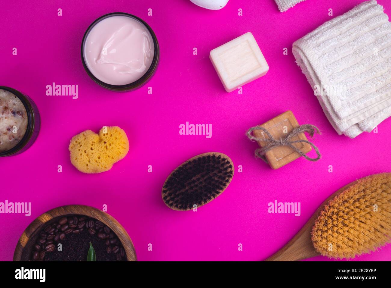 Scrub, lozione, saponi, salvietta di cotone, guanto per la cura del corpo su sfondo rosa. Kit spa eco-compatibile, a disposizione piatta Foto Stock