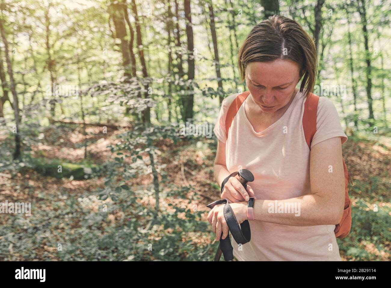 Hiker femmina che controlla il tracker intelligente di idoneità mentre trekking attraverso la foresta Foto Stock