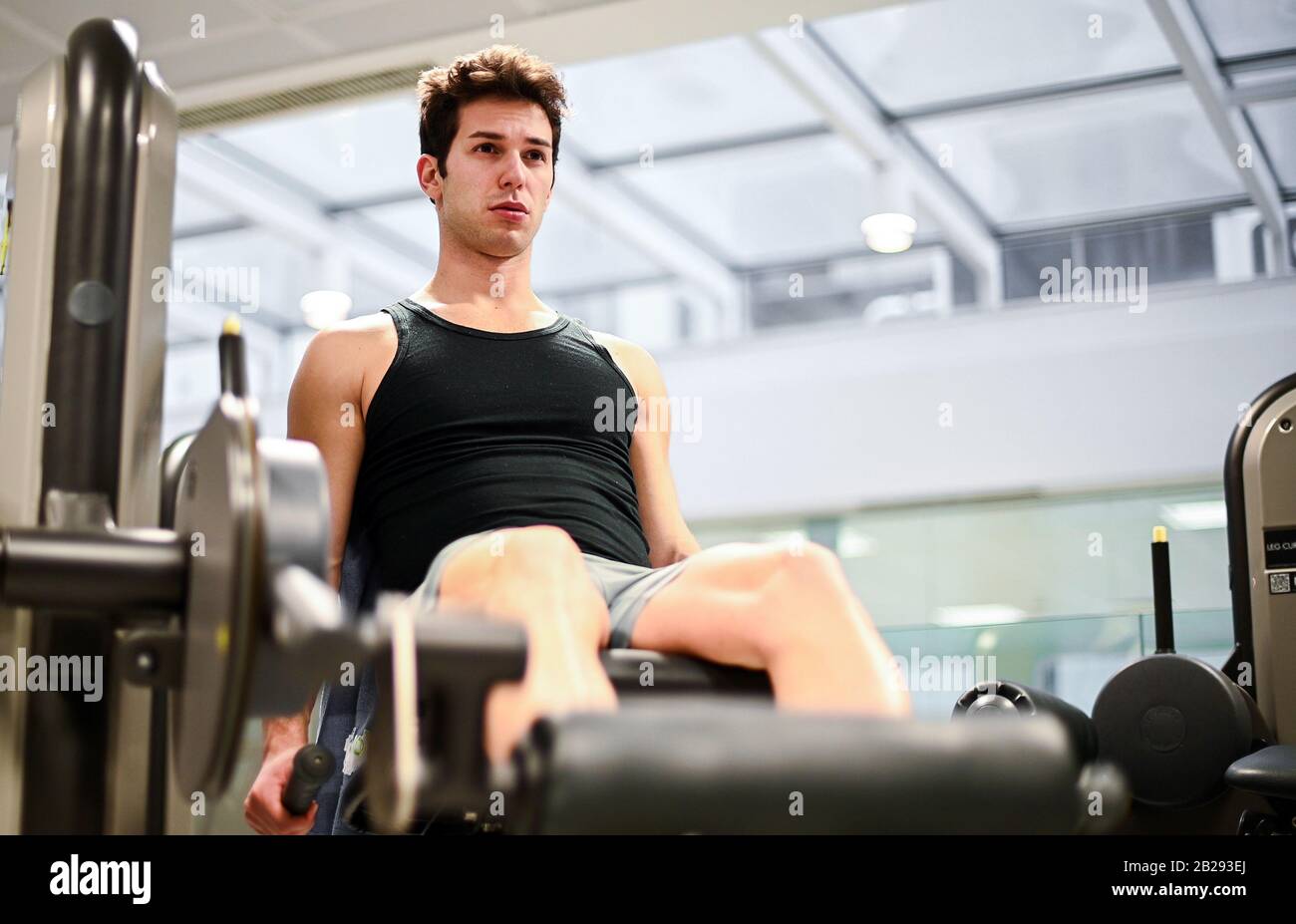 Palestra seduta macchina arricciamento gambe esercizio uomo in palestra Foto Stock