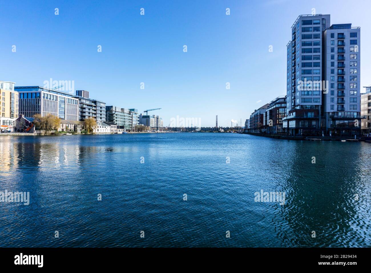 Grand Canal Docks, Irlanda, con la Millennium Tower sulla destra e in lontananza le torri gemelle di Poolbeg e l'inceneritore di Dublino. Foto Stock
