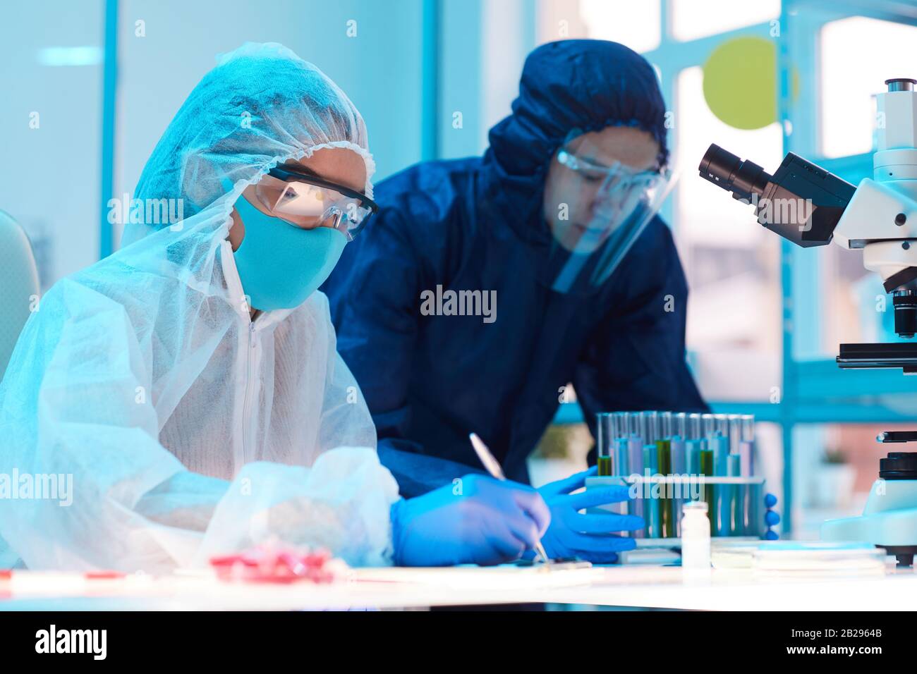 Ritratto della vista laterale di due scienziati che indossano attrezzature a rischio biologico lavorando alla ricerca in laboratorio medico, copia spazio Foto Stock