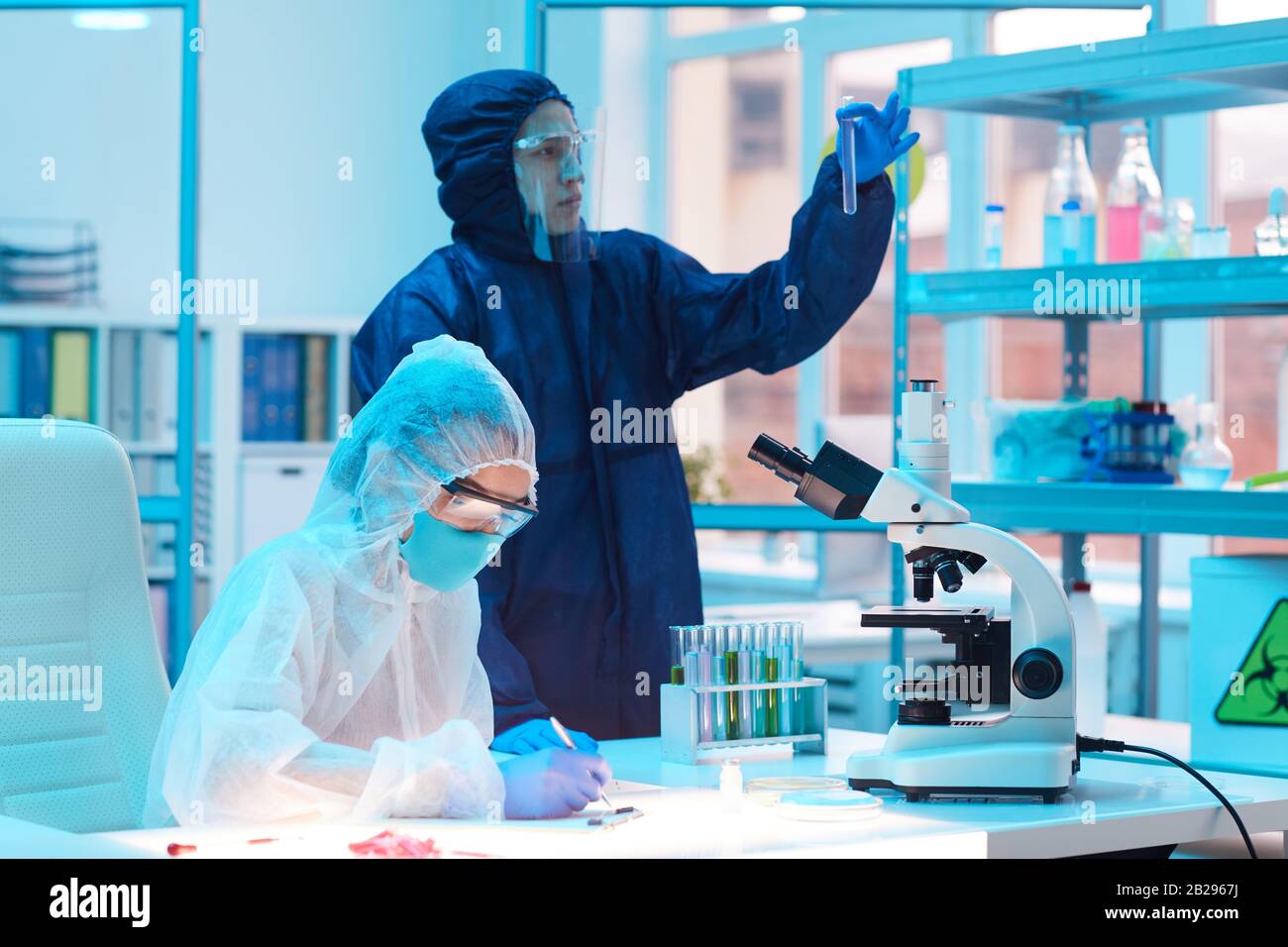 Ritratto di due scienziati che indossano attrezzature a rischio biologico lavorando alla ricerca in laboratorio medico, copia spazio Foto Stock