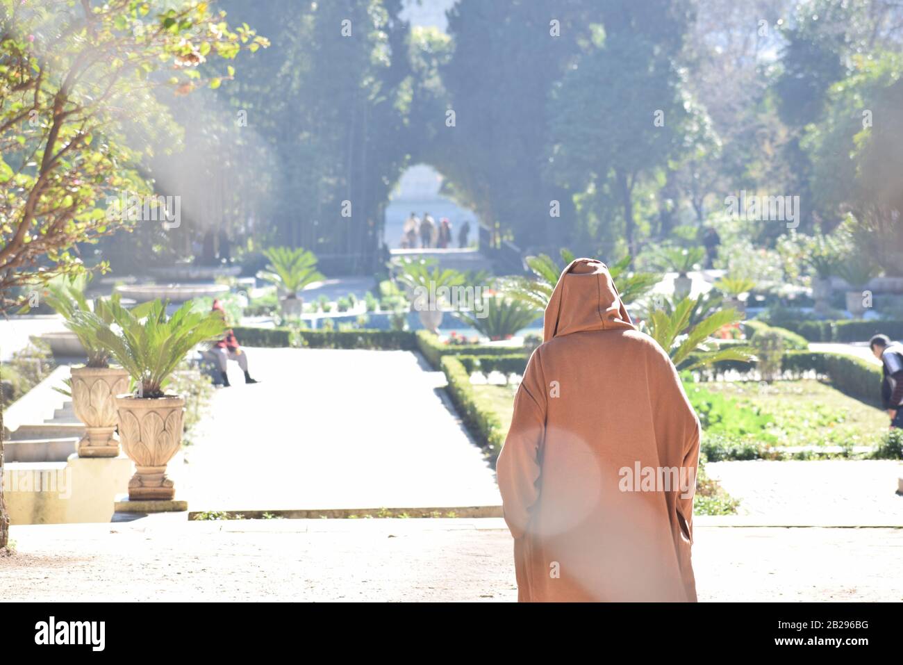 Un uomo marocchino anziano attraversa i giardini in una Djellaba Foto Stock