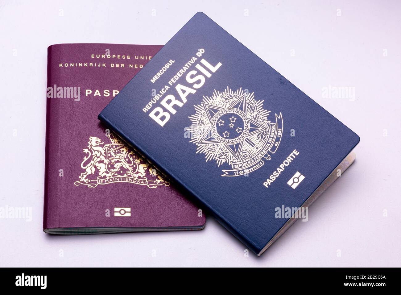 Brasiliano in cima a europeo - olandese - passaporto su una superficie luminosa sfondo. Concetto di doppia nazionalità. Foto Stock