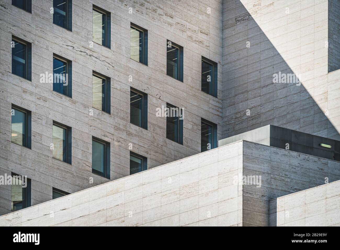 Vista della geometria architettonica di un edificio d'affari costruito in marmo travertino romano Foto Stock