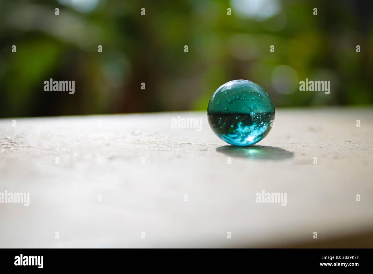 Un vetro trasparente con marmi verdi sulla parte superiore del muro con un buon sfondo sfocato con un concetto creativo e spazio di area di testo Foto Stock