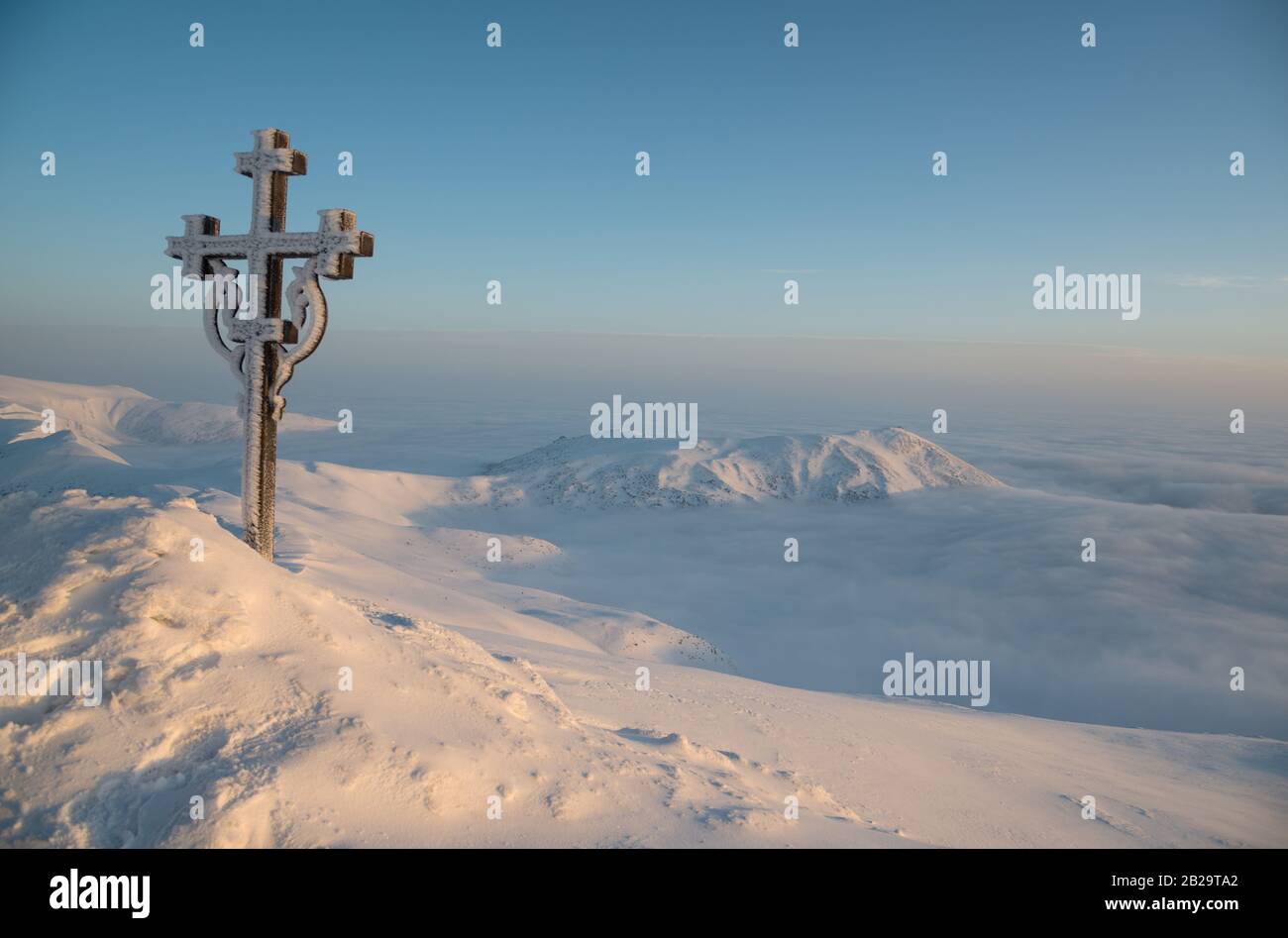 Il cristianesimo attraversa nuvole e montagne innevate. Giorno di nascita. Foto Stock